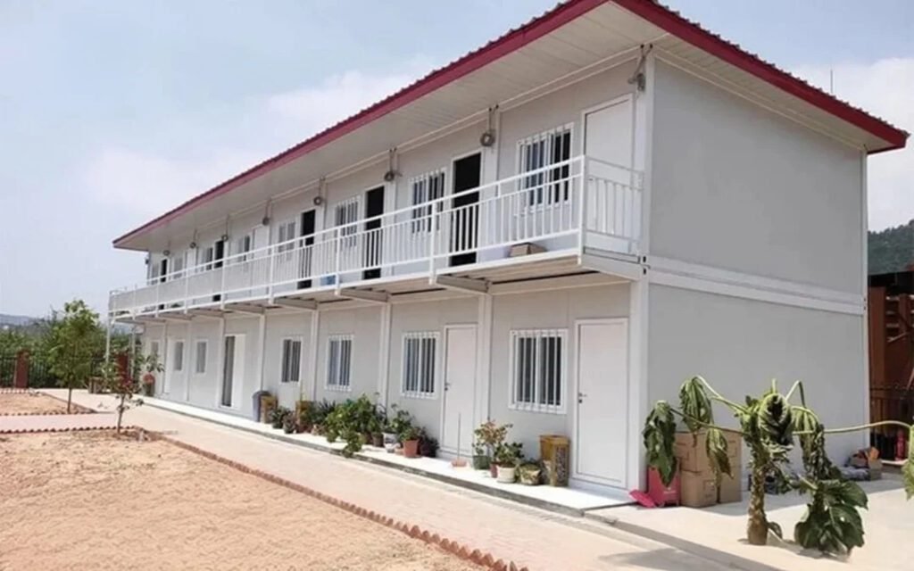 Jasa bangun rumah kategori desain modern. Fasad rumah dua lantai dengan balkon putih, atap merah. Bangun rumah berdasarkan kebutuhan.